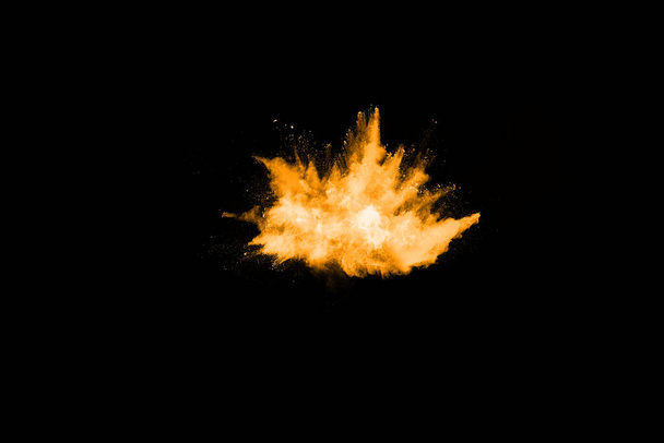 Congelar el movimiento de la explosión de polvo amarillo aislado sobre fondo negro. - Foto, Imagen