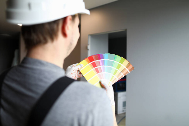 Constructor en casco sostiene paleta de colores cerca de la pared
 - Foto, imagen