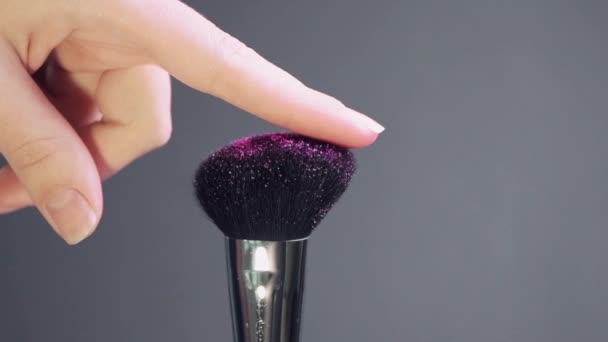 Touch of a female hand, finger to a cosmetic brush with sparkles. - Séquence, vidéo