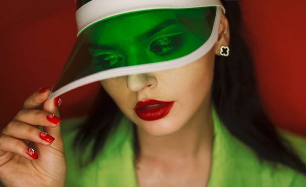 Yeşil elbiseli, kafasında güneş gözlüğü olan turuncu arka planda bir kız. - Fotoğraf, Görsel