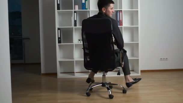A lawyer in a black shirt sits on a chair in his office with panoramic windows and counts the money earned today - Video