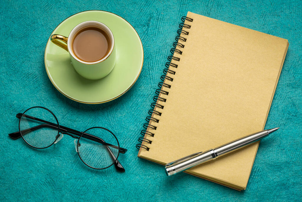 desktop flat lay with a blank spiral notebook, reading glasses and a cup of coffee, business and workspace concept - Photo, Image