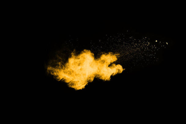 Замораживание движения взрыва желтой пыли на черном фоне. - Фото, изображение