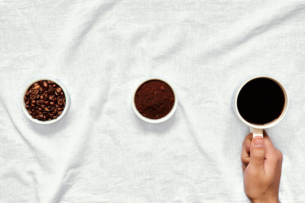 whole and ground coffee beans holding a cup - Fotografie, Obrázek