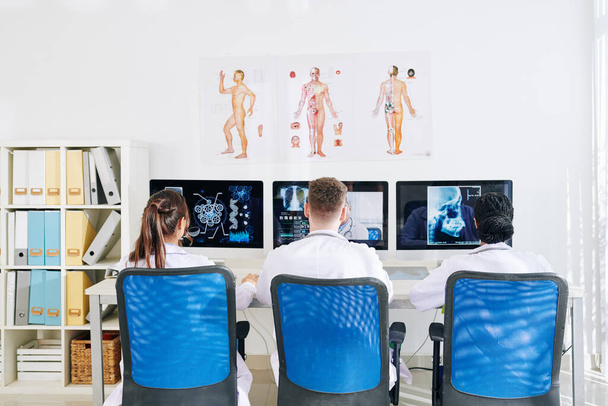 Группа студентов-медиков смотрит онлайн-вебинар на компьютерах и знакомится с новейшими и эффективными методами диагностики и лечения - Фото, изображение