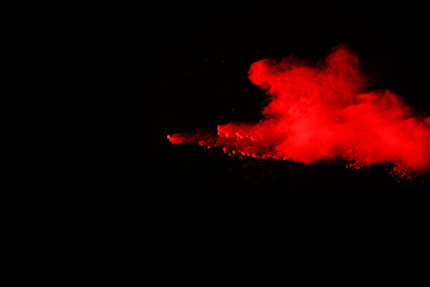 αφηρημένη έκρηξη κόκκινης σκόνης σε μαύρο φόντο.αφηρημένη κόκκινη σκόνη πιτσιλισμένη σε μαύρο φόντο. Παγωμένη κίνηση κόκκινης σκόνης που εκρήγνυται. - Φωτογραφία, εικόνα