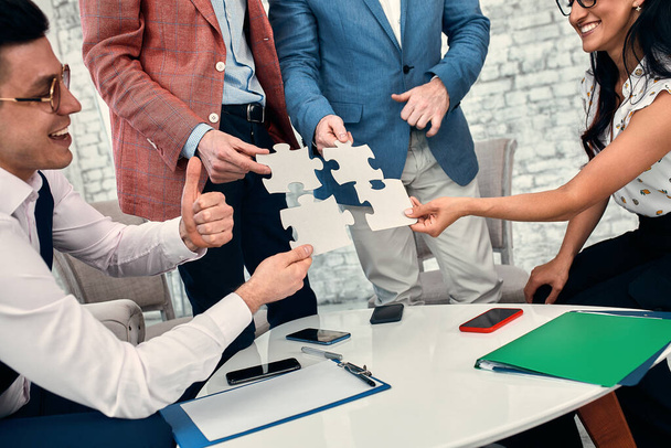 Cropped image of businesspeople joining puzzle pieces in office - Photo, Image