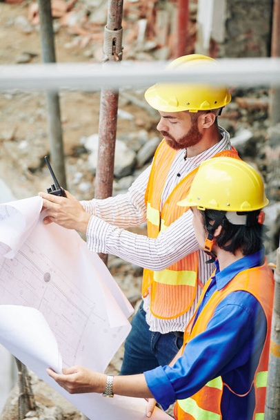 Серьезные строители в каскаде проверки дома план при работе на строительной площадке - Фото, изображение
