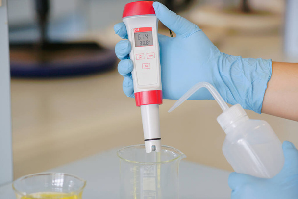 Naukowiec pracuje nad roztworem chemicznym z uchwytem pH miernika  - Zdjęcie, obraz