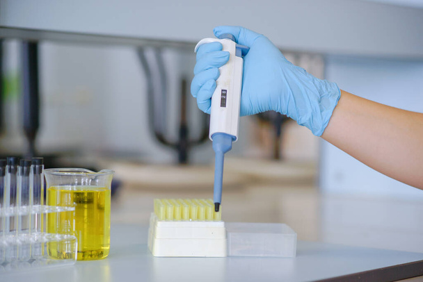 Wissenschaftler im Chemielabor mit automatischer Pipette. Mit blauen Handschuhen. - Foto, Bild