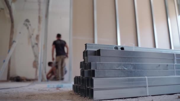 家のアパートの再建、建設チームの労働者は、石膏ボードを組み立てるための金属建設プロファイルをインストールします。アパートの壁の改造、家のプロジェクトを変更します。建築業及び建築 - 映像、動画