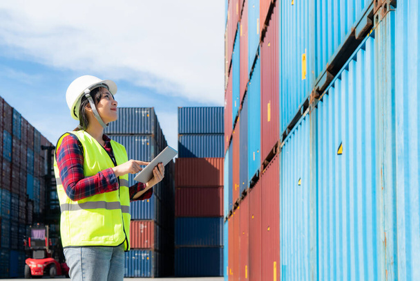 Жінка-інженер або менеджер Формана в контейнерному депо працює з цифровим планшетом для контролю і перевірки промислових контейнерних ярдів для логістики морського імпорту експортний судноплавний бізнес в порту - Фото, зображення