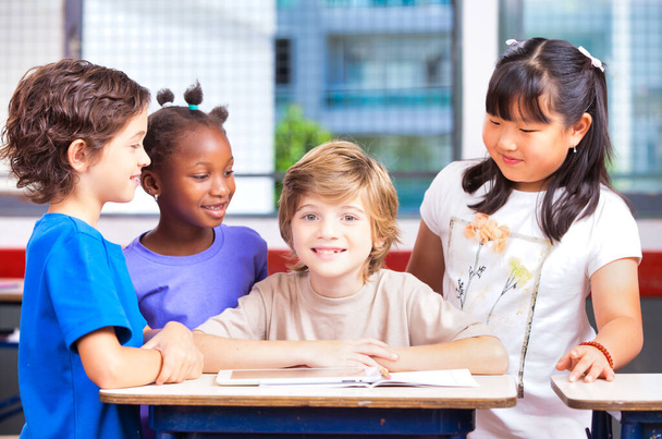 Elementary school scene. Multi ethnic classmates in the classroom learning together. Back to school concept - Photo, Image