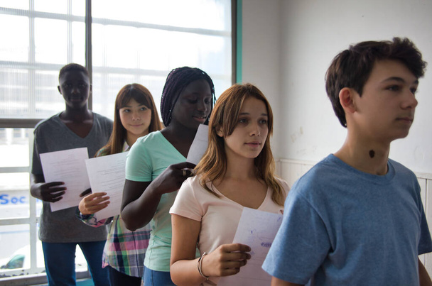 Tieners op school. Multi-etnische klaslokaal leveren test. - Foto, afbeelding