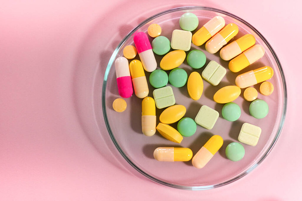 Фармацевтические таблетки в чашке Петри на столе                                                               - Фото, изображение