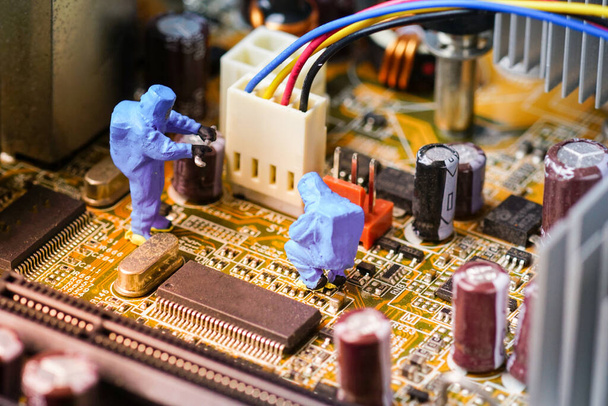 技術者はコンピュータのメインボードで修理します。ミニチュア人.                               - 写真・画像