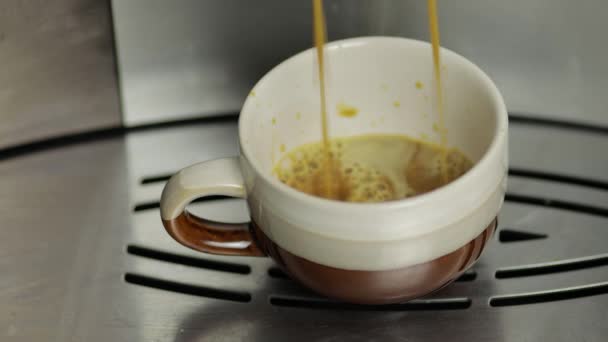 Espresso schot gieten uit koffiezetapparaat in kleine witte en bruine beker. Close-up beelden - Video