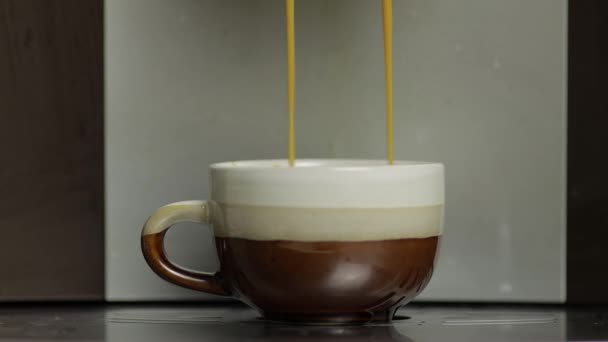 Tir expresso coulant de la machine à café dans une petite tasse blanche et brune. Fermer les images - Séquence, vidéo