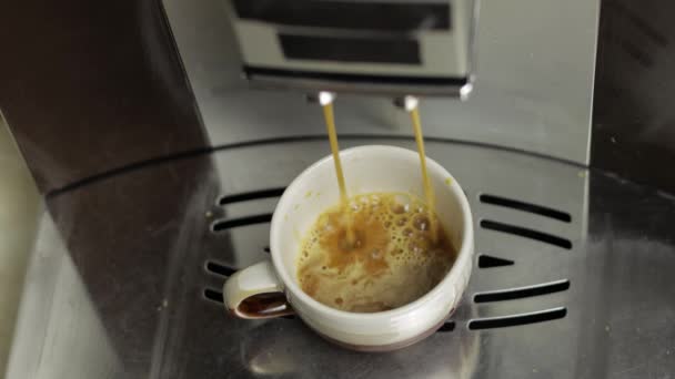 Espresso strzał wylewa się z ekspres do kawy w małym białym i brązowym kubku. Zamknij nagranie. - Materiał filmowy, wideo