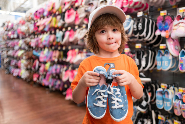 Lächelndes amerikanisches Kind mit Schuhen Kinder im Schuhgeschäft - Foto, Bild