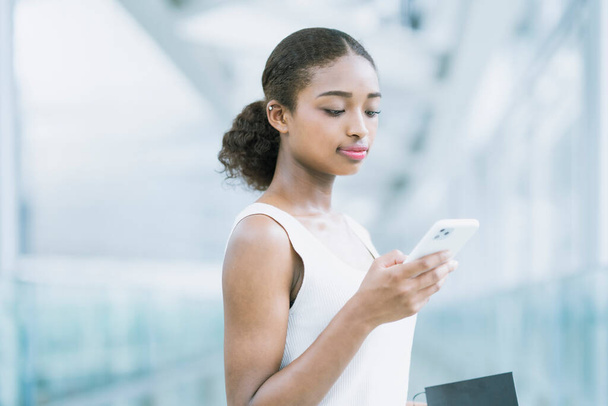 スマートフォンの画面を見て営業している若いビジネス女性 - 写真・画像