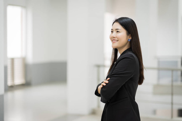 Portrait d'une jeune femme d'affaires joyeuse surfant sur les réseaux sociaux sur tablette numérique devant le bureau pendant la pause. Femme d'affaires asiatique debout dans un immeuble de bureaux. Photo de stock d'affaires - Photo, image