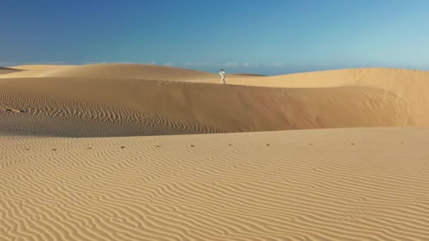4K slow motion di duna di sabbia con motivo ondulato e donna che cammina sullo sfondo - Filmati, video