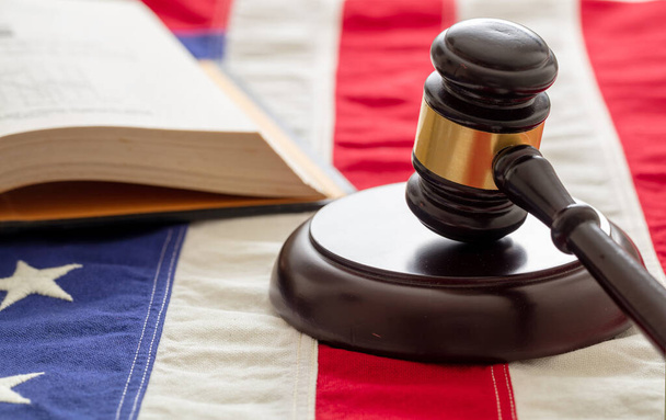 Юридическое образование в США. Судья молоток и открытая книга на фоне флага США. Концепция правосудия в США
 - Фото, изображение