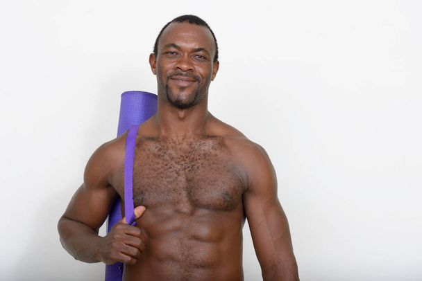 Studio shot of handsome muscular bearded African man shirtless against white background - Photo, image