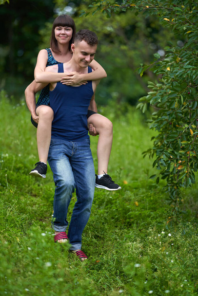Young couple having fun with a piggyback ride outdoor in the nature - Foto, imagen