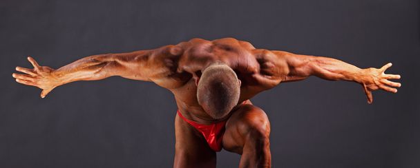 Hombre musculoso con los brazos extendidos hacia un lado y la cabeza hacia abajo
 - Foto, imagen
