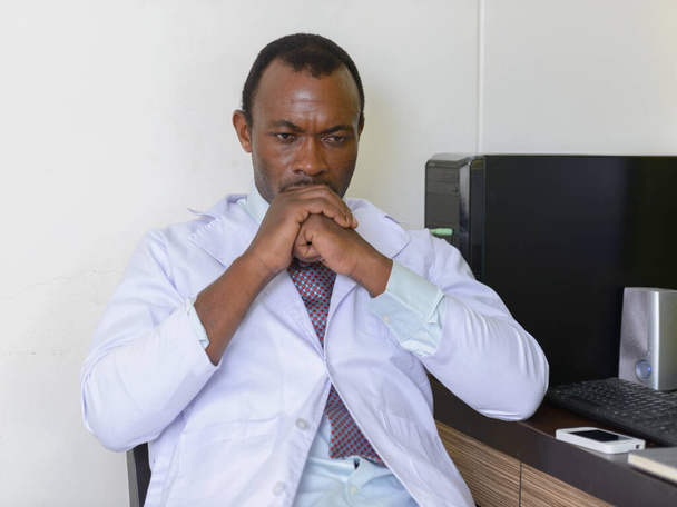 Portrait of handsome bearded African man doctor working in the office indoors - Foto, Bild