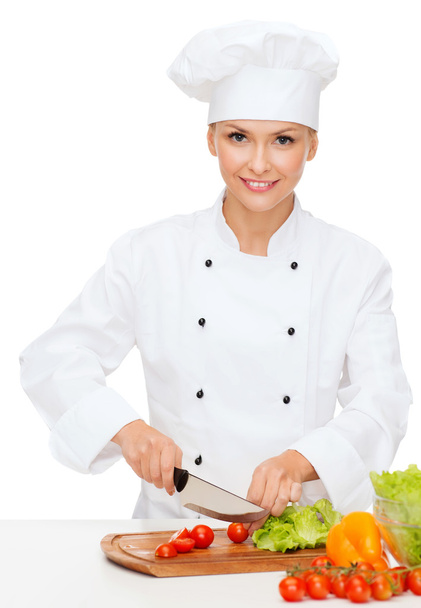 Smiling female chef chopping vagetables - Zdjęcie, obraz