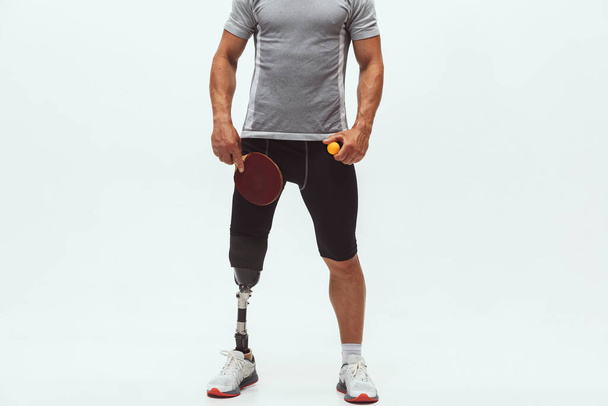 Athlete with disabilities or amputee isolated on white studio background. Professional male table tennis player with leg prosthesis training and practicing in studio. - Foto, Imagem