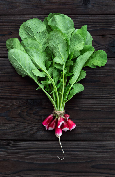 Radish core on a dark wooden table. A bunch of eaten radishes. Concept of delicious fresh radish. - 写真・画像