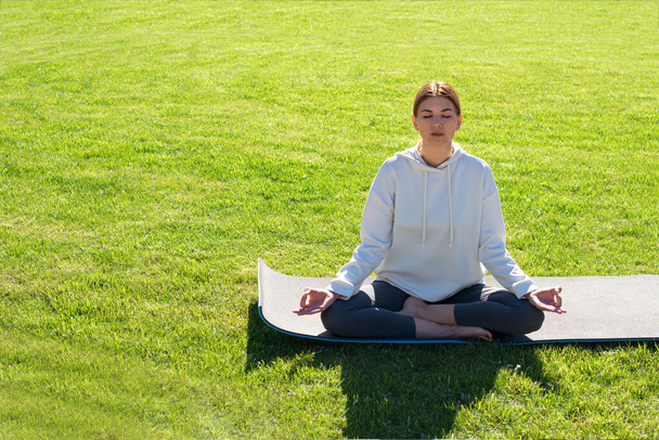Žena cvičí jógu venku na trávě. Bentální zdraví, snížení úzkosti, vnitřní klid - Fotografie, Obrázek