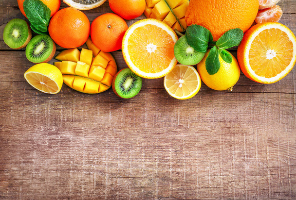 Assortiment de sources riches en vitamine A sur fond bois : kiwis, mangue, granadille, citrons, oranges, mandarines. Vue de dessus. Espace de copie. - Photo, image