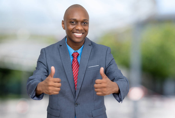 Successful african american businessman showing thumbs up outdoors in the city - Photo, image