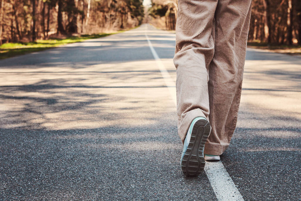 Frau läuft auf der asphaltierten Straße im Kiefernwald. Kopieren Sie Platz für Ihren Text - Foto, Bild