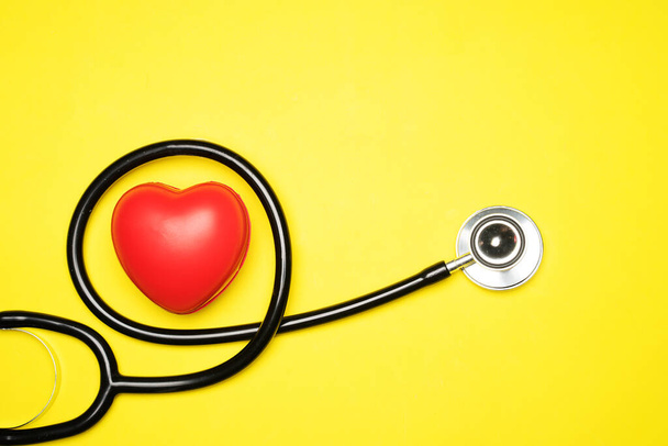 Healthcare or medical concept. Stethoscope and a red heart on a yellow background. Flat lay or top view. - Valokuva, kuva