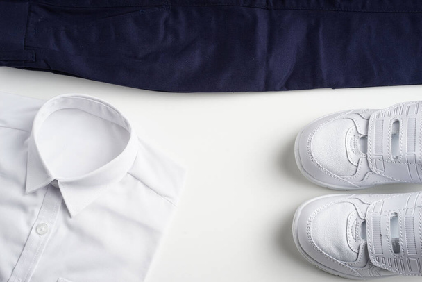 Disposición creativa de uniformes escolares y zapatos aislados sobre fondo blanco. Concepto de regreso a la escuela
. - Foto, imagen