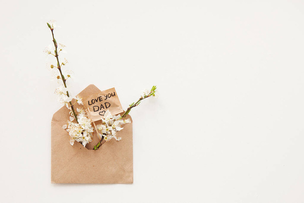 Вітальна листівка з текстом Люблю тебе батько в ремісничому конверті з букетами весняних гілок і квітами для батька. Концепція Міжнародний день батька, день народження, екологія. Мінімалізм
 - Фото, зображення