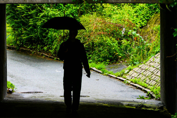 Gothenburg, Sweden  A person with an umbrella in silhouette walks in an underpass. - Photo, Image