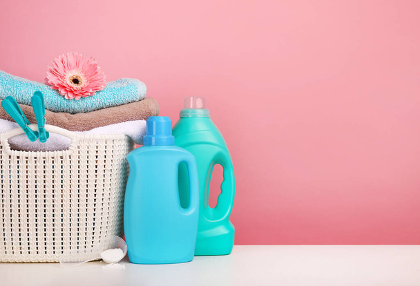 Detergent with washing powder and towels over pink wall - 写真・画像