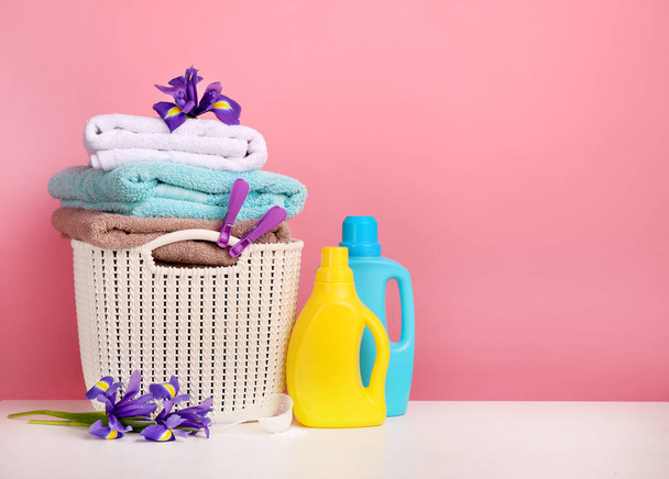 Detergente con detergente en polvo y toallas sobre pared rosa
 - Foto, imagen