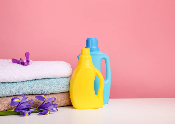 Waschmittel mit Waschmittel und Handtüchern über rosa Wand - Foto, Bild