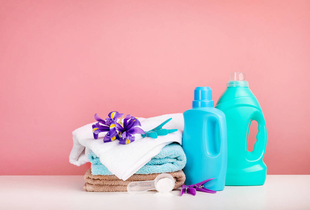 Detergent with washing powder and towels over pink wall - Fotografie, Obrázek