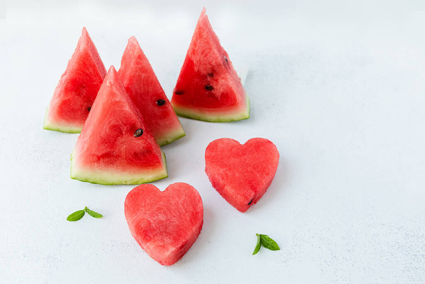 Scheiben aufgeschnittener reifer, saftiger, süßer Wassermelone auf einer hellen Vorderseite. Das Konzept des leichten, sommerlichen Essens. - Foto, Bild