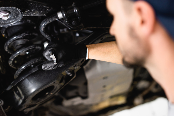 selective focus of mechanic holding wrench while fixing vehicle  - Photo, Image