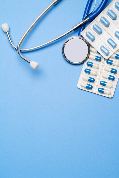 blister of pills capsiles and stethoscope isolated on blue background - Photo, Image